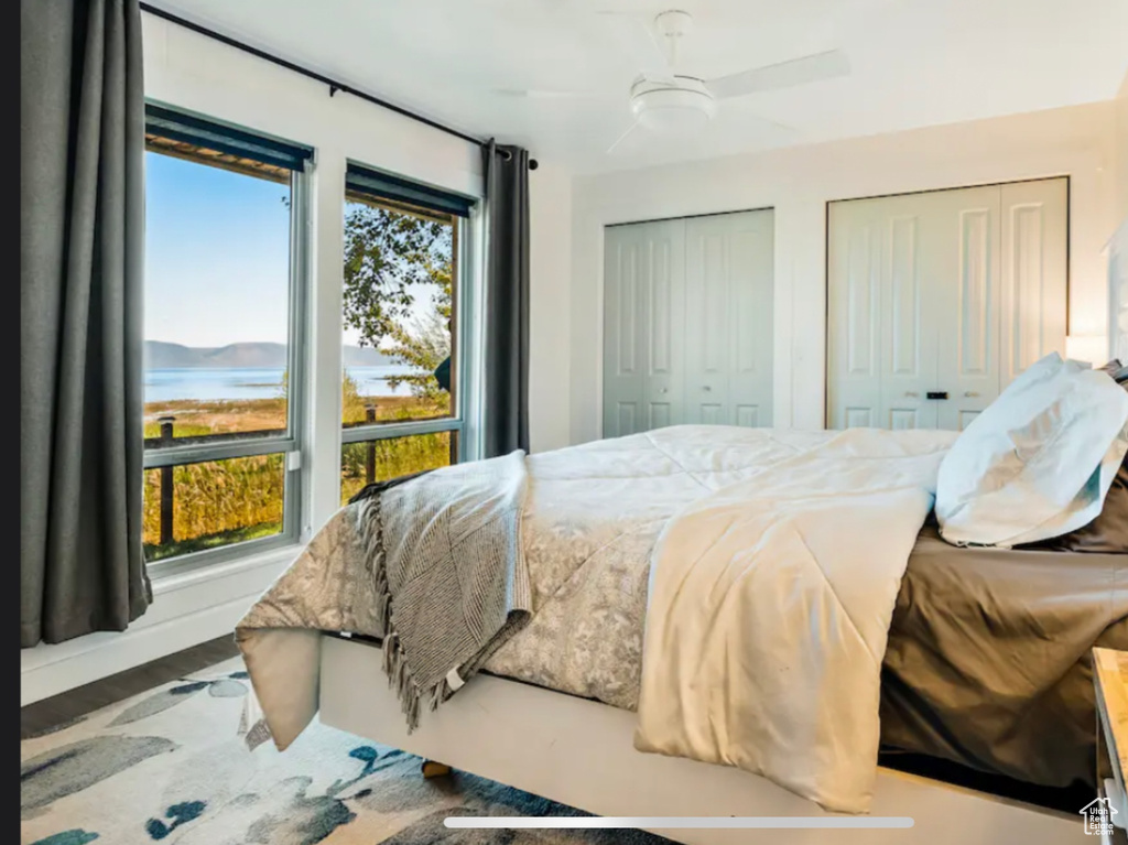 Bedroom with a water view, multiple windows, multiple closets, and ceiling fan