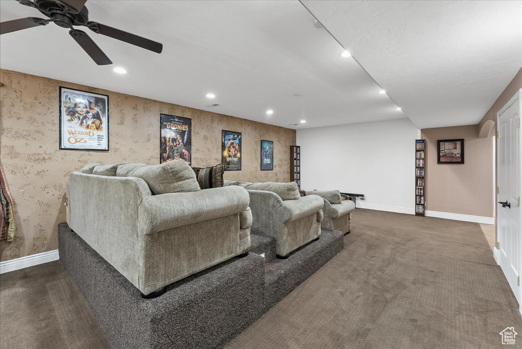 Carpeted cinema room featuring ceiling fan