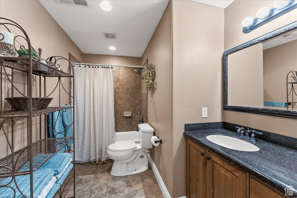 Full bathroom featuring vanity, toilet, tile flooring, and shower / tub combo with curtain