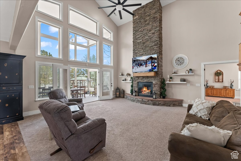 Living room featuring a stone fireplace, hardwood / wood-style floors, high vaulted ceiling, and ceiling fan