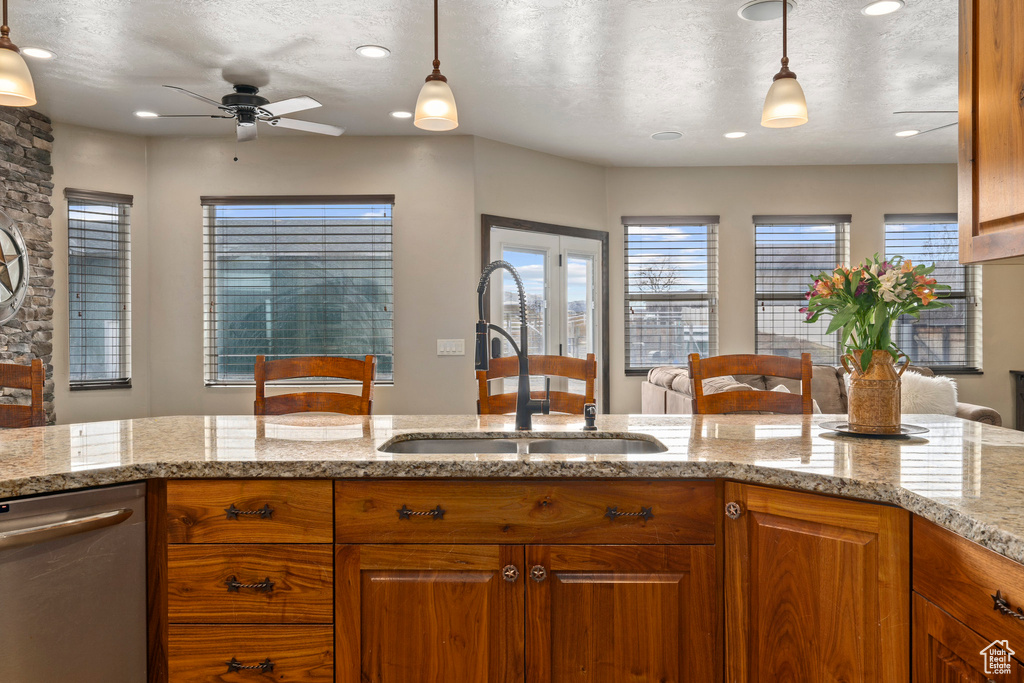 Kitchen featuring light stone counters, decorative light fixtures, and ceiling fan