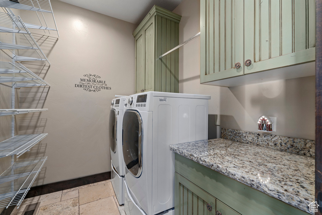 Laundry room with cabinets, light tile floors, and washer and dryer
