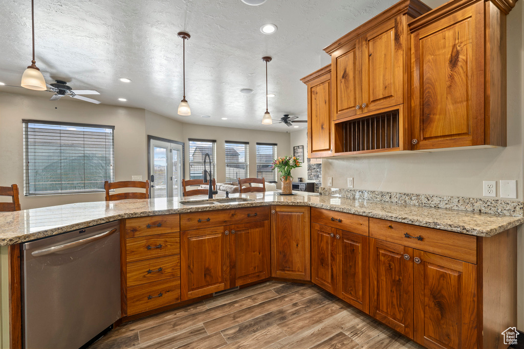 Kitchen featuring ceiling fan, light stone counters, stainless steel dishwasher, hardwood / wood-style flooring, and sink