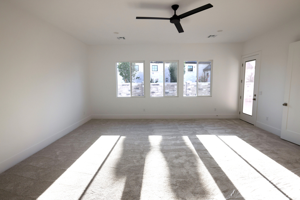 Spare room featuring light carpet, healthy amount of natural light, and a ceiling fan