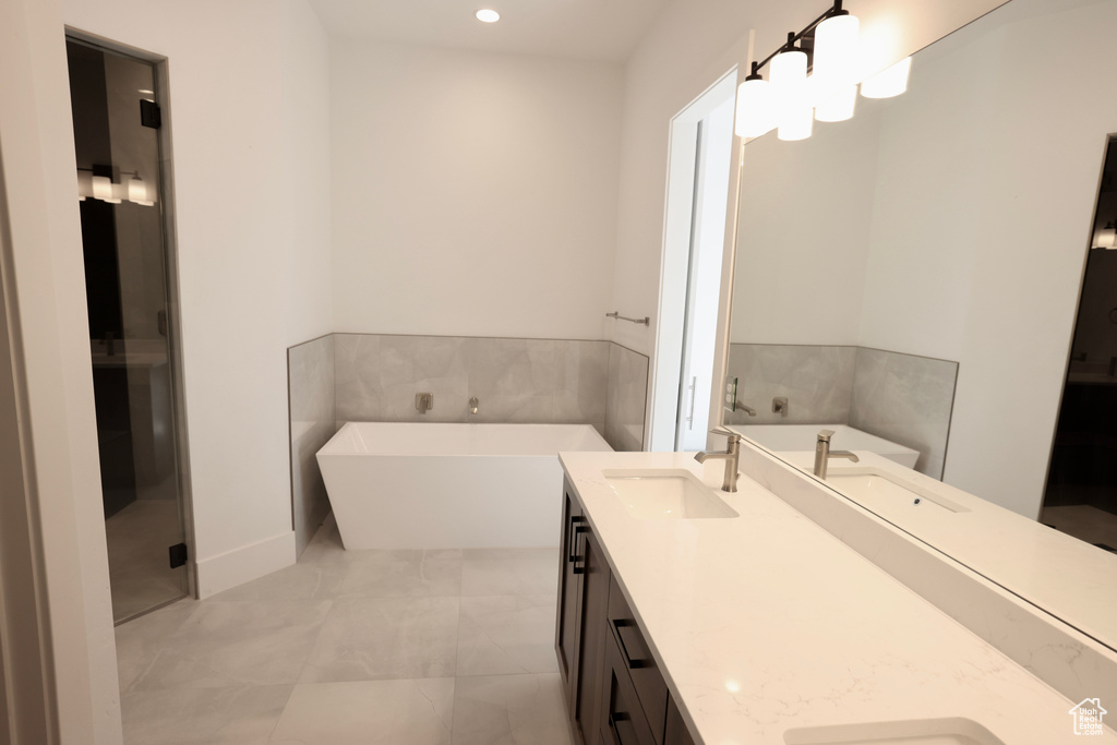 Bathroom with double vanity, a soaking tub, and recessed lighting