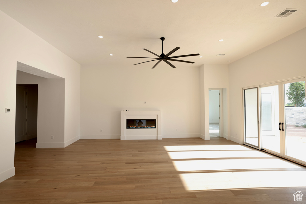 Unfurnished living room featuring recessed lighting, a ceiling fan, light wood-style flooring, and a glass covered fireplace