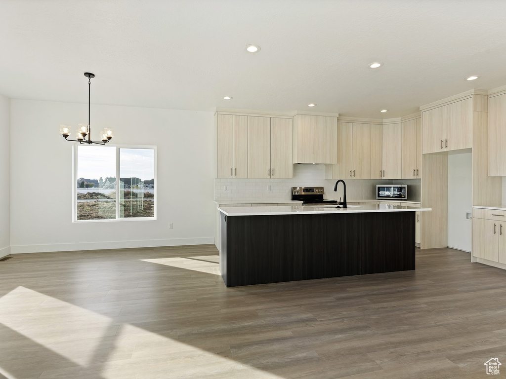 Kitchen with decorative light fixtures, a chandelier, light hardwood / wood-style flooring, stainless steel appliances, and a kitchen island with sink