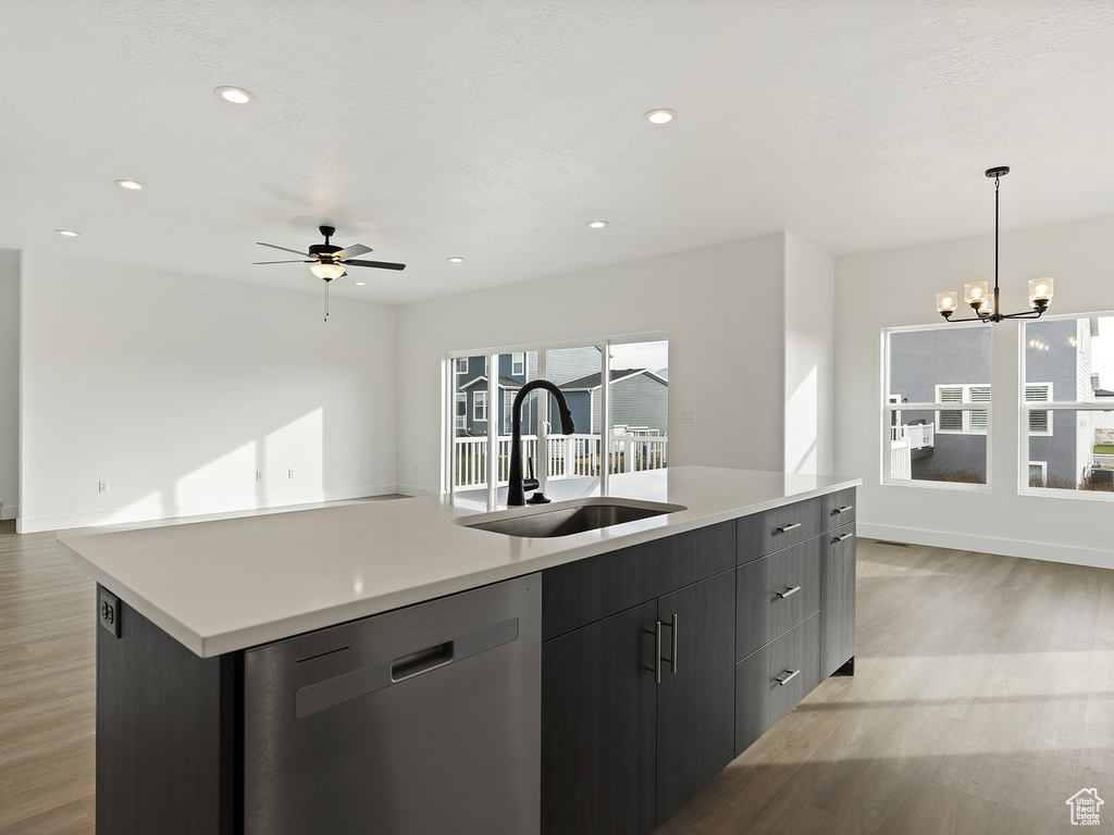 Kitchen featuring pendant lighting, light wood-type flooring, ceiling fan with notable chandelier, dishwasher, and sink