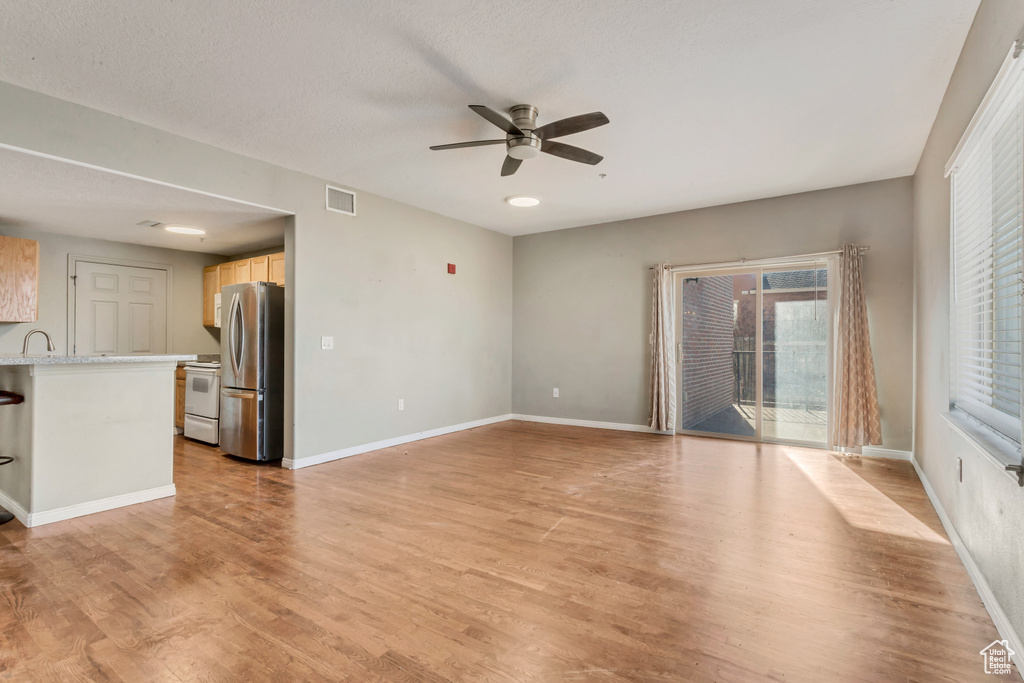 Empty room featuring light hardwood / wood-style flooring, sink, and ceiling fan
