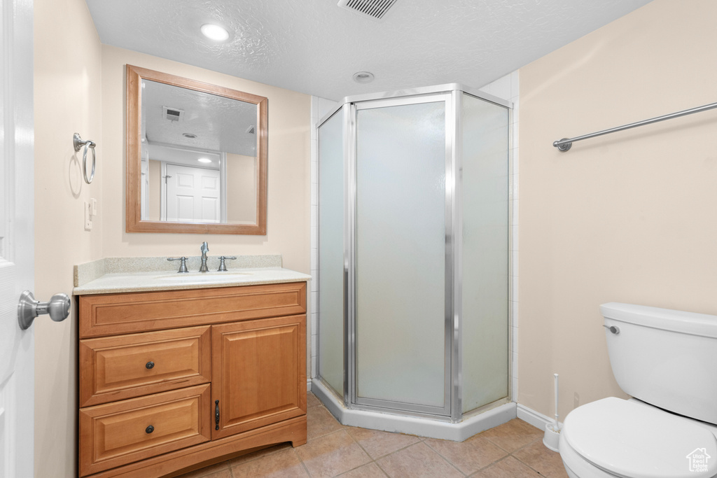 Bathroom with toilet, oversized vanity, tile floors, an enclosed shower, and a textured ceiling