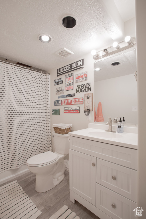 Bathroom with large vanity, toilet, and a textured ceiling