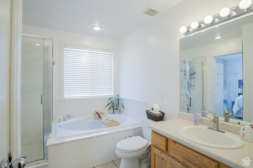 Full bathroom with tile floors, toilet, vanity, and separate shower and tub