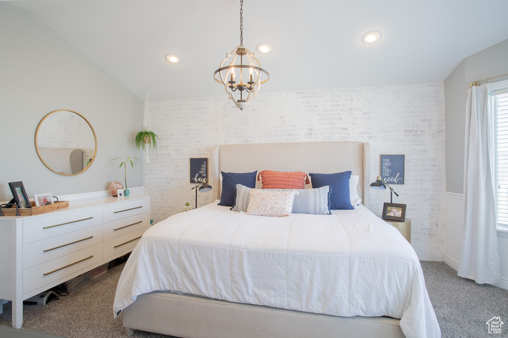 Bedroom featuring an inviting chandelier, brick wall, and lofted ceiling