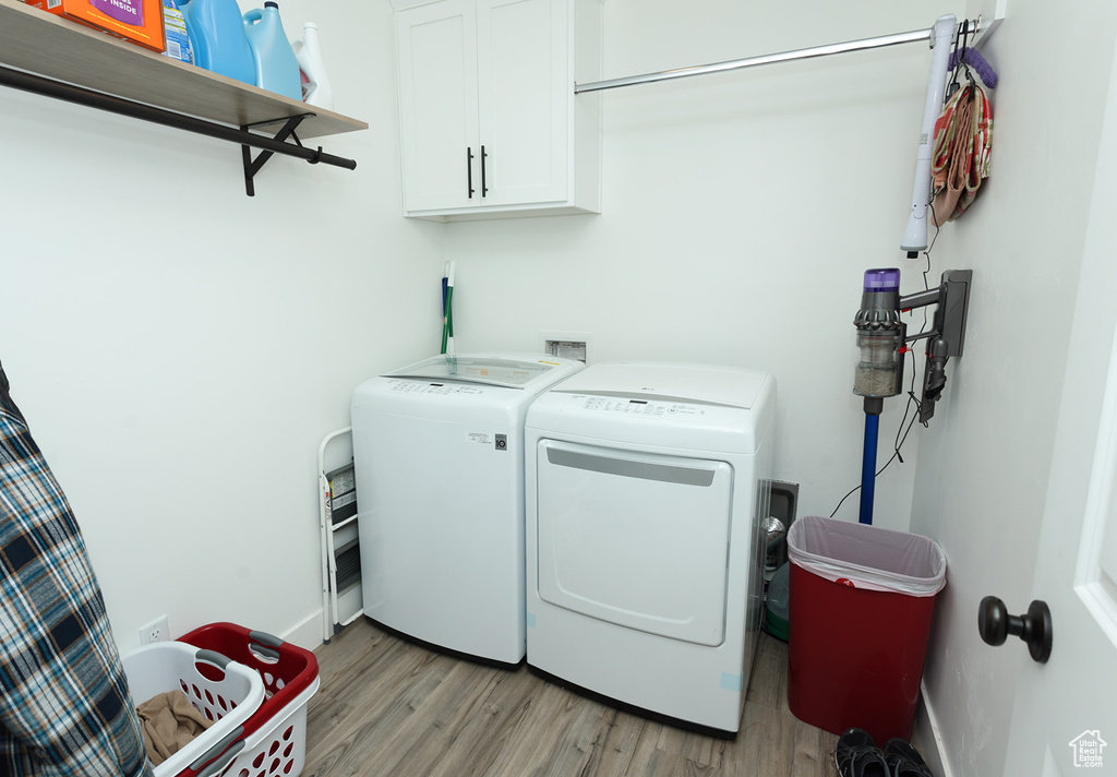 Laundry area featuring separate washer and dryer, cabinets, light wood-type flooring, and washer hookup