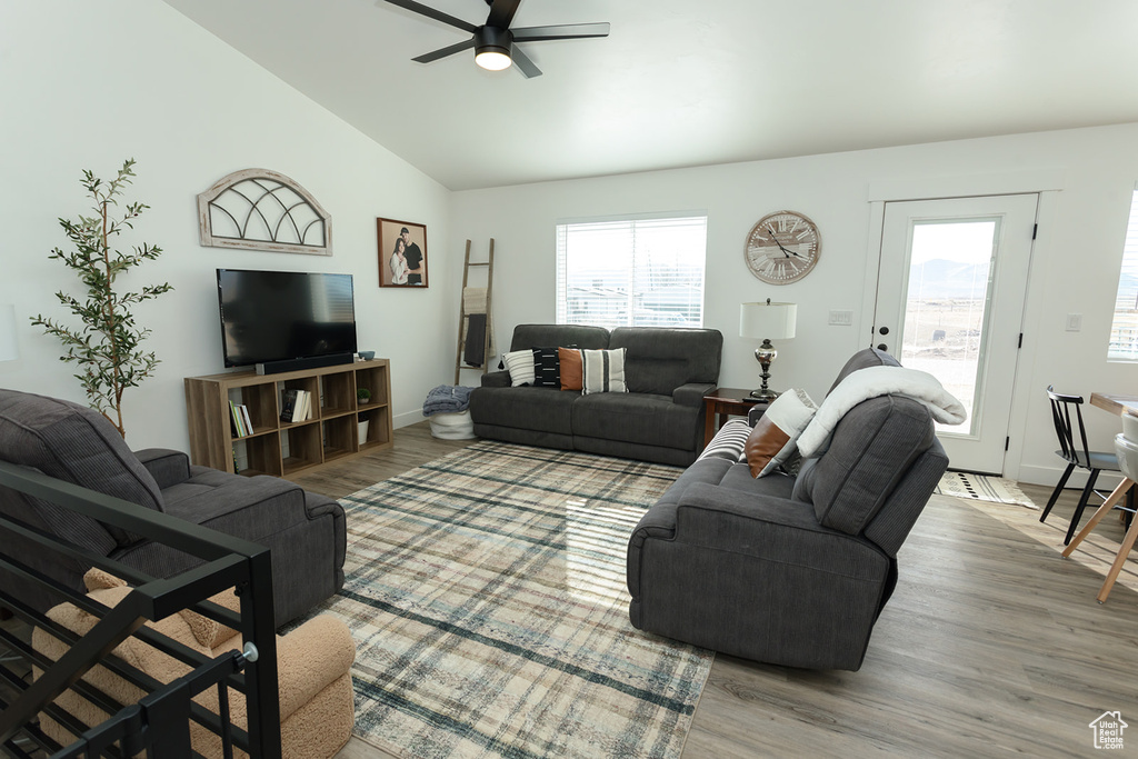Living room with light hardwood / wood-style floors, a healthy amount of sunlight, high vaulted ceiling, and ceiling fan
