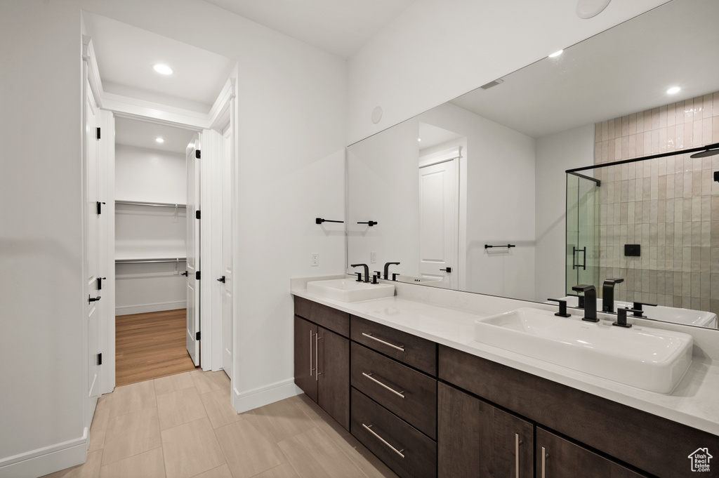 Bathroom with a shower with shower door, dual bowl vanity, and tile flooring