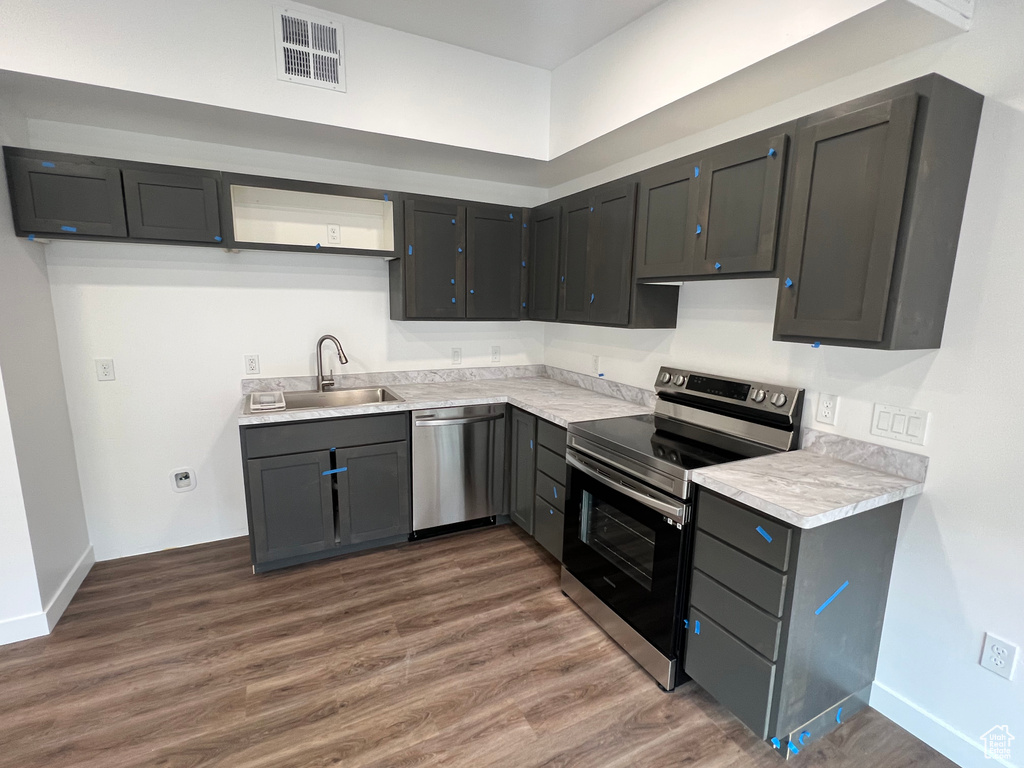 Kitchen with sink, appliances with stainless steel finishes, gray cabinetry, and hardwood / wood-style flooring