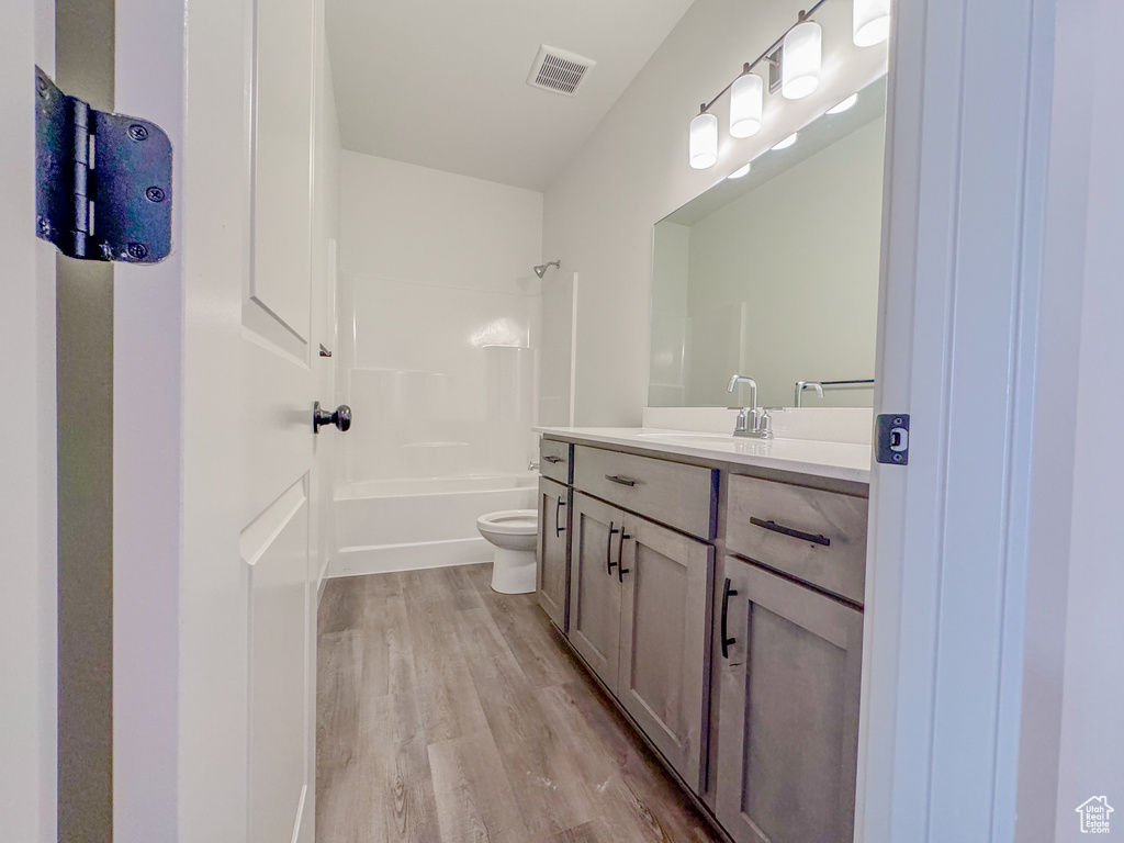 Full bathroom featuring vanity, toilet, washtub / shower combination, and wood-type flooring