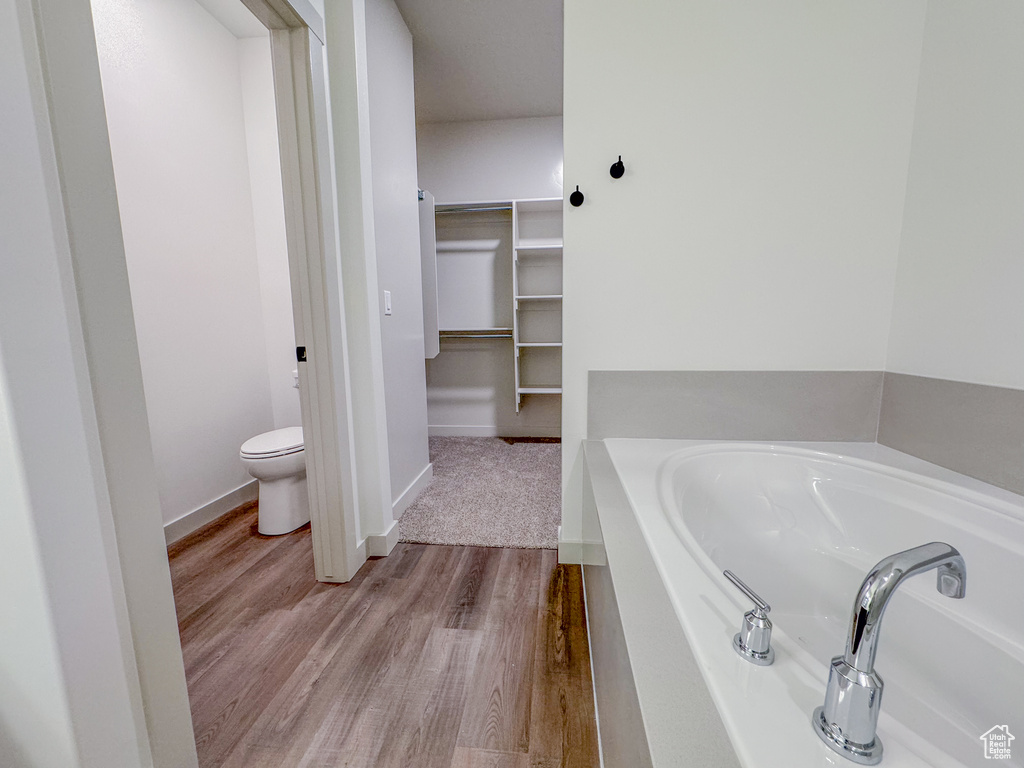 Bathroom with hardwood / wood-style floors, a washtub, and toilet