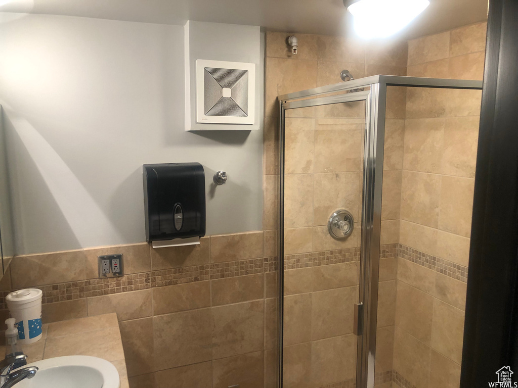Bathroom featuring a shower with shower door and sink