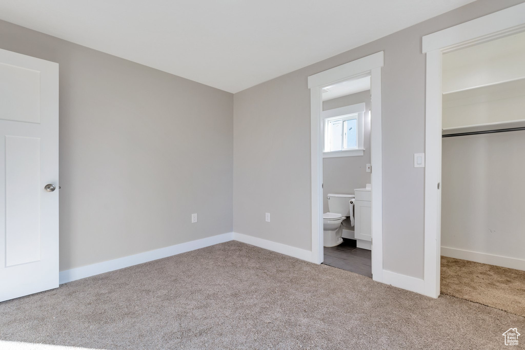 Unfurnished bedroom with ensuite bathroom, a closet, and light carpet
