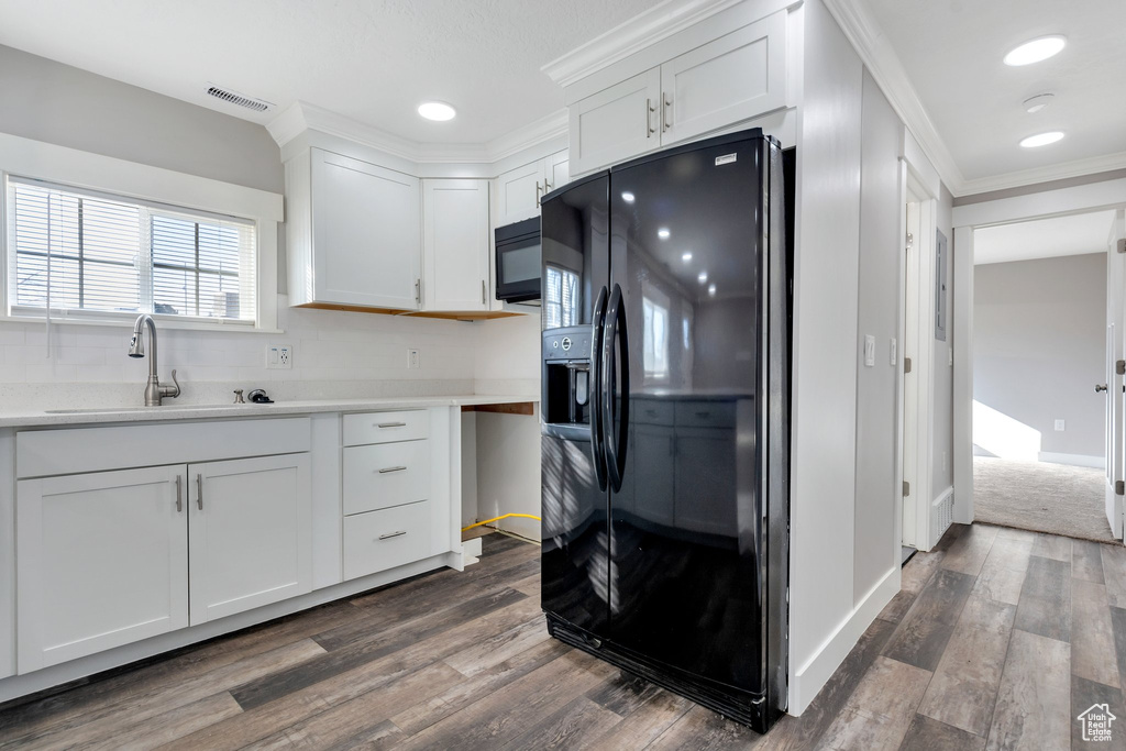 Kitchen with black appliances, dark hardwood / wood-style flooring, white cabinets, and sink