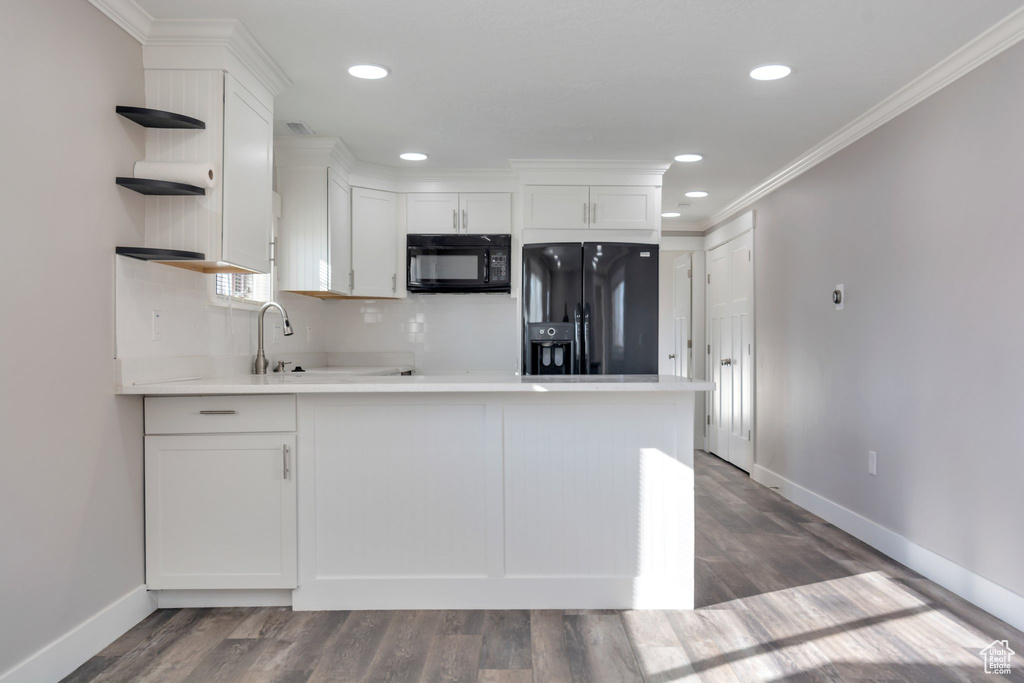 Kitchen with crown molding, black appliances, backsplash, dark hardwood / wood-style floors, and white cabinetry