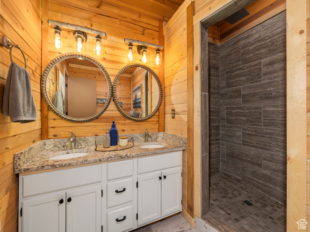 Bathroom with wood walls, double vanity, and tiled shower
