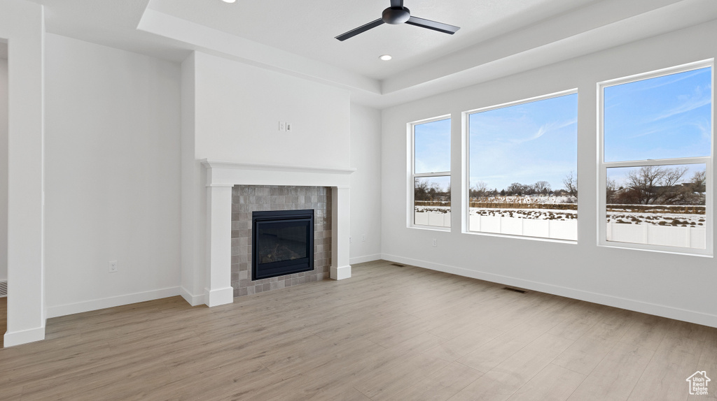 Unfurnished living room with light wood-type flooring, a fireplace, and ceiling fan