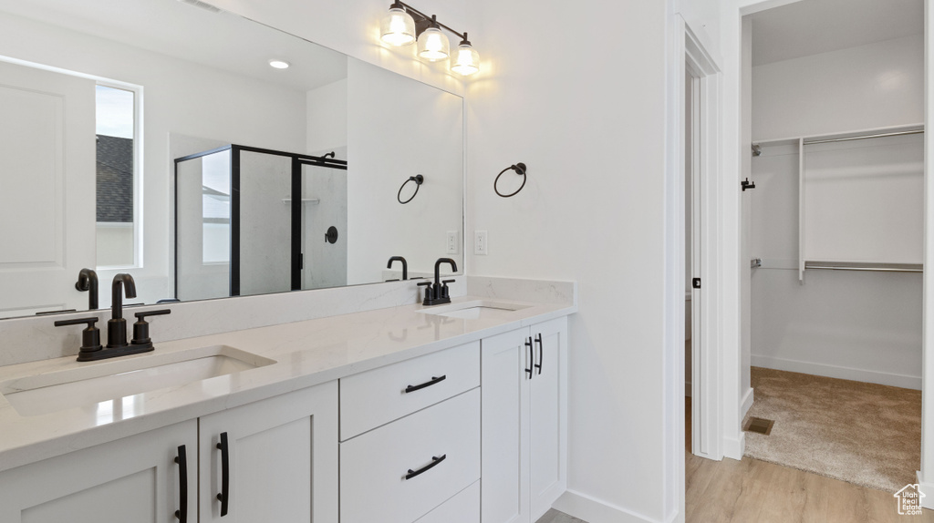 Bathroom featuring double vanity, hardwood / wood-style floors, and a shower with door