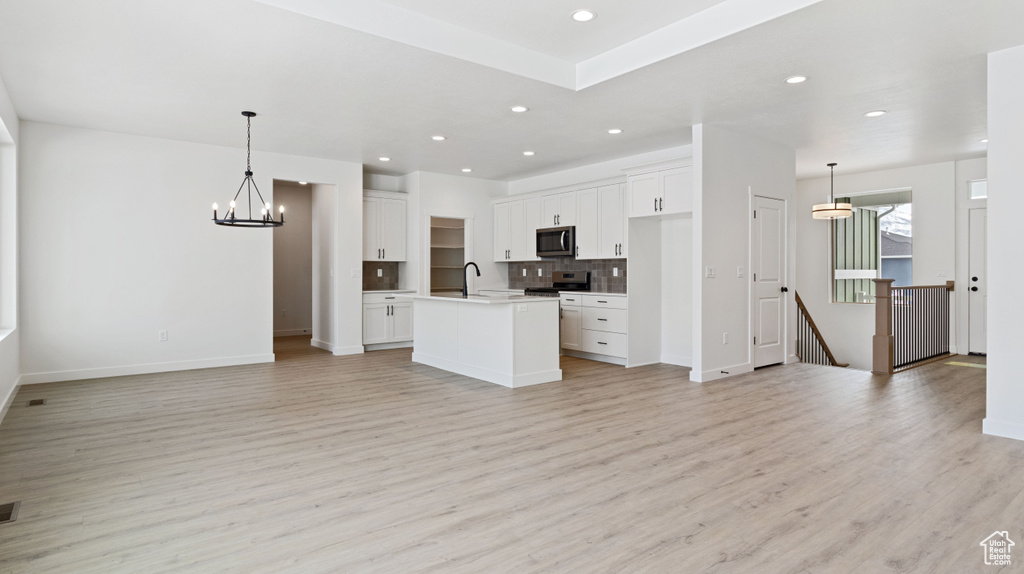 Kitchen with pendant lighting, an inviting chandelier, white cabinets, and light wood-type flooring