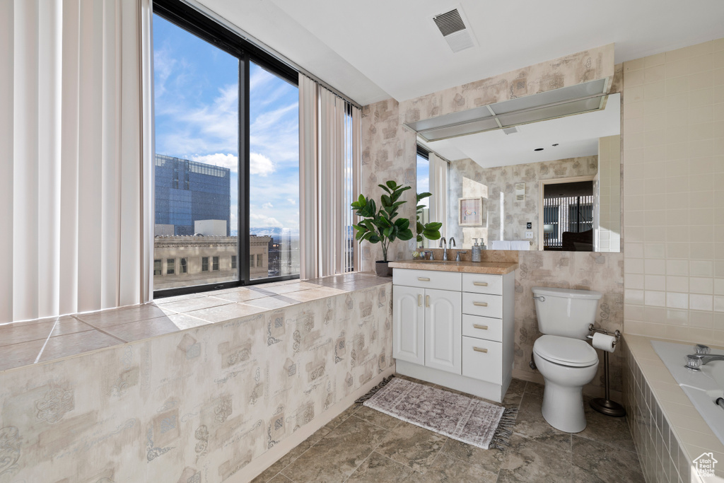 Bathroom with tile walls, vanity, toilet, and tile flooring