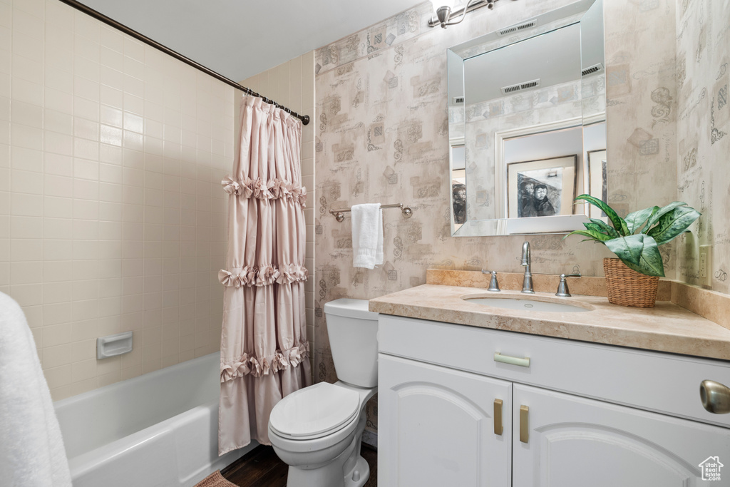 Full bathroom with shower / tub combo with curtain, large vanity, and toilet