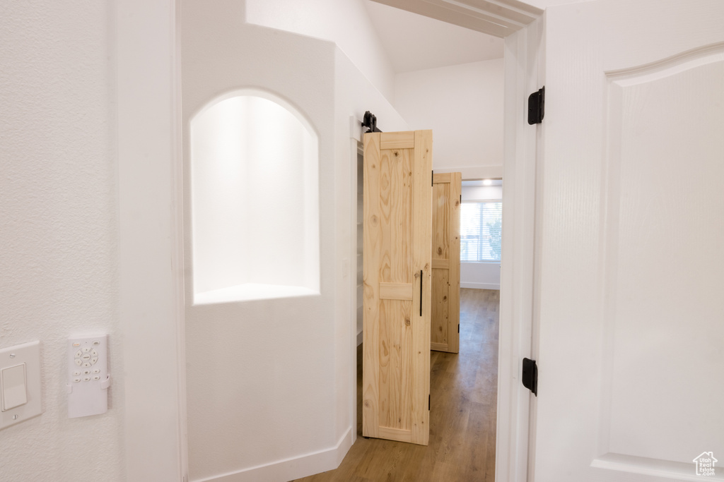 Hall with a barn door and light hardwood / wood-style flooring