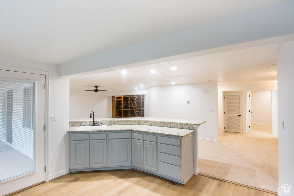 Kitchen featuring sink, light stone countertops, light carpet, and ceiling fan