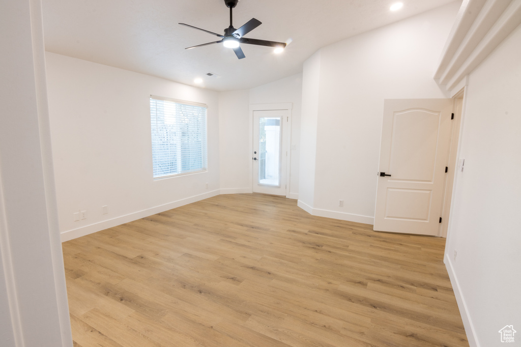 Empty room with light hardwood / wood-style flooring, lofted ceiling, and ceiling fan