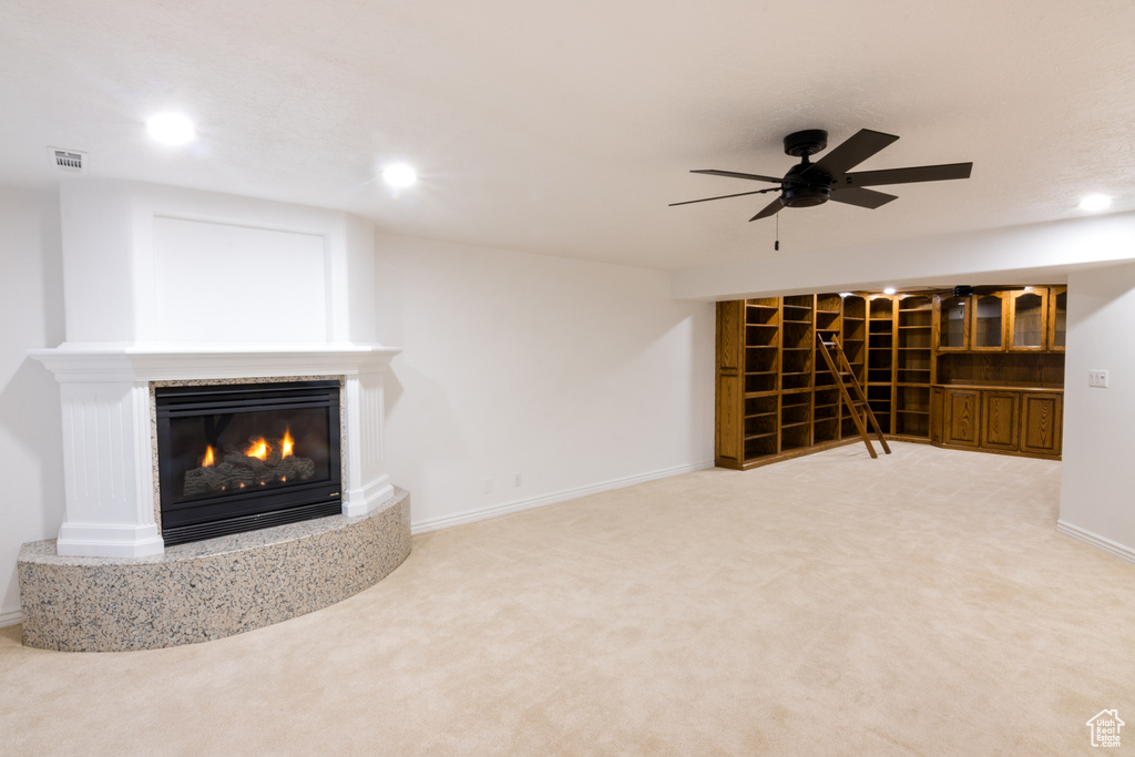 Unfurnished living room featuring carpet and ceiling fan