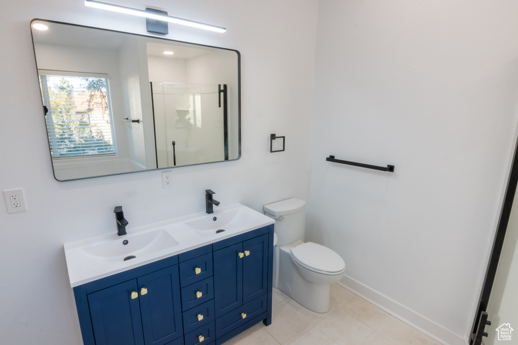 Bathroom featuring toilet, large vanity, a shower with door, tile floors, and double sink