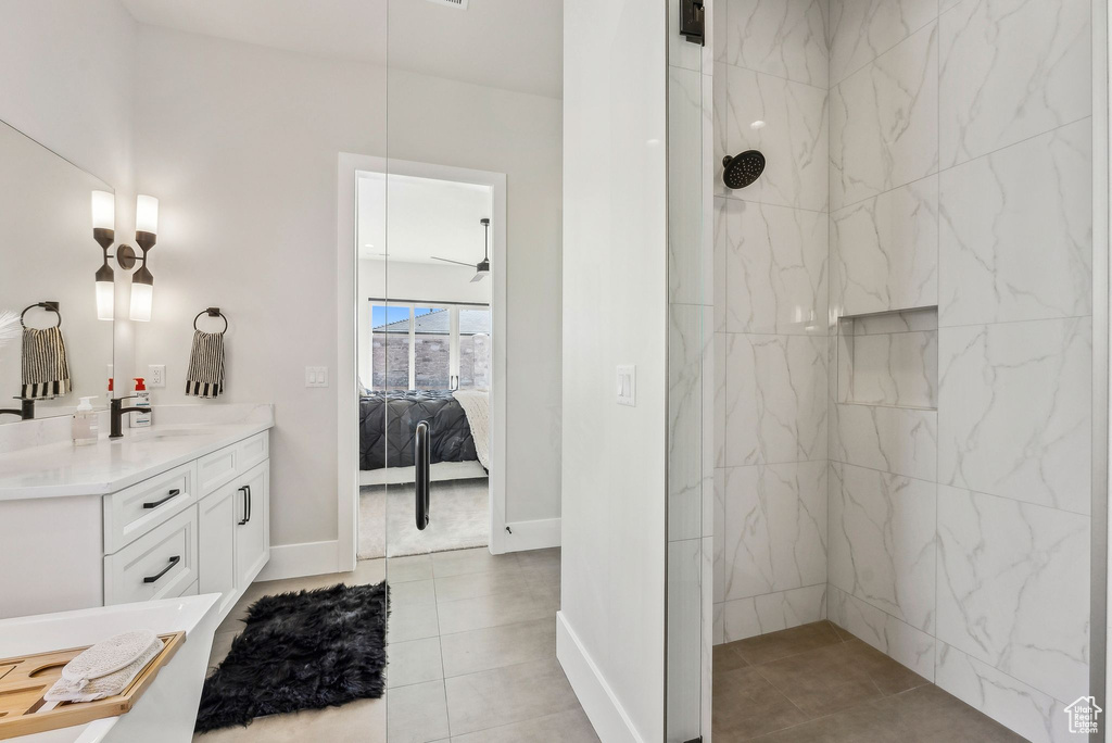 Ensuite bathroom featuring vanity, tile patterned floors, a marble finish shower, baseboards, and ensuite bathroom