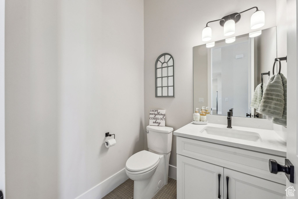 Bathroom with toilet, tile patterned floors, baseboards, and vanity