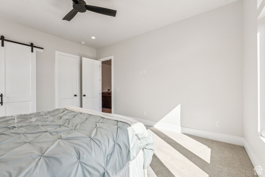 Carpeted bedroom with baseboards, a ceiling fan, and a barn door