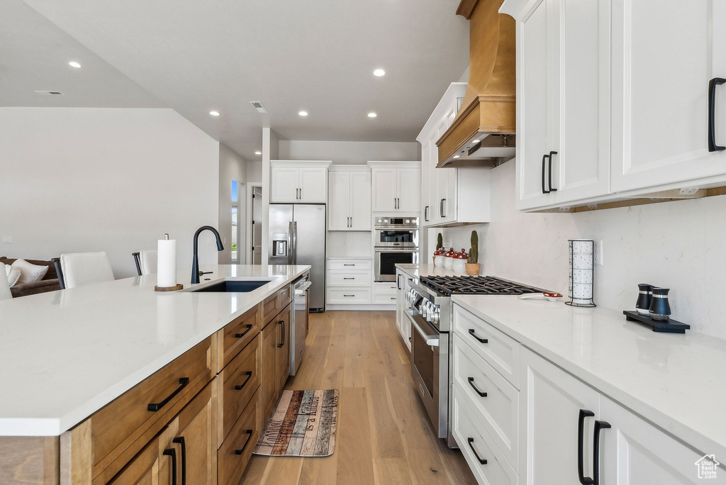 Kitchen with stainless steel appliances, recessed lighting, a sink, and custom range hood