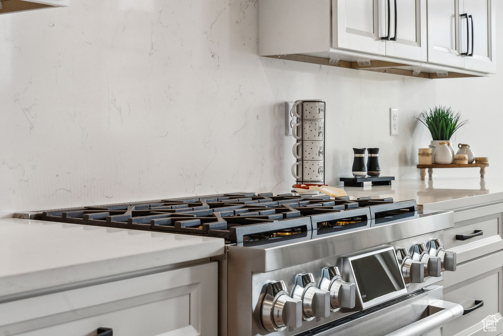 Room details with light countertops, white cabinets, and range