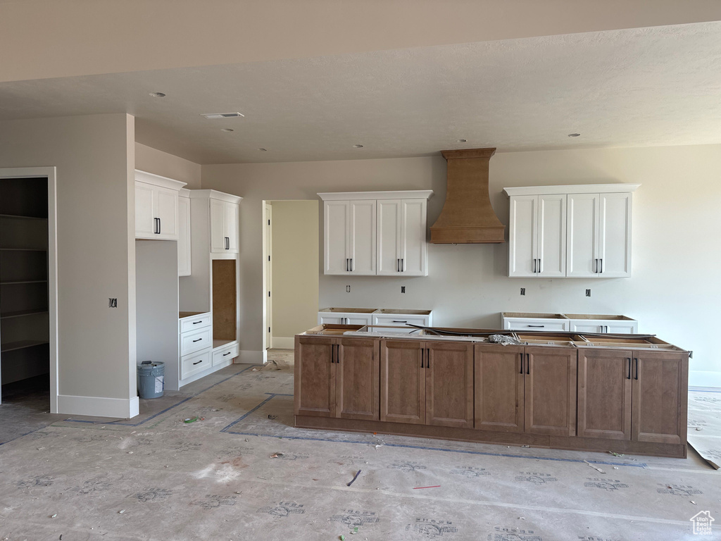 Kitchen featuring a center island, custom exhaust hood, and white cabinetry