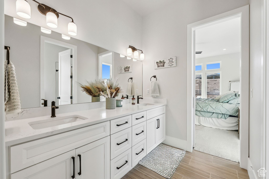 Bathroom with wood finished floors, double vanity, a sink, and ensuite bath
