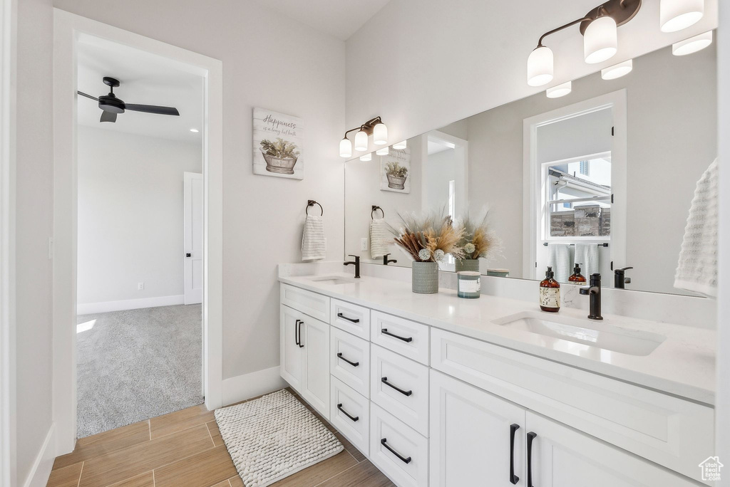Bathroom featuring double vanity, a ceiling fan, a sink, and wood finished floors