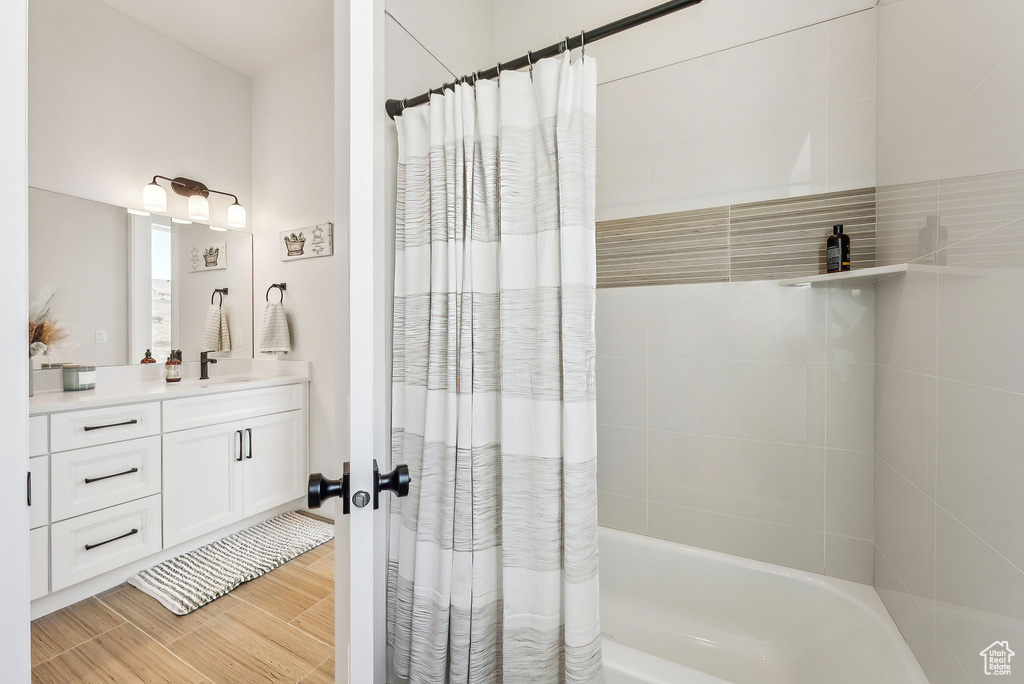 Full bath featuring vanity, wood finished floors, and shower / tub combo with curtain