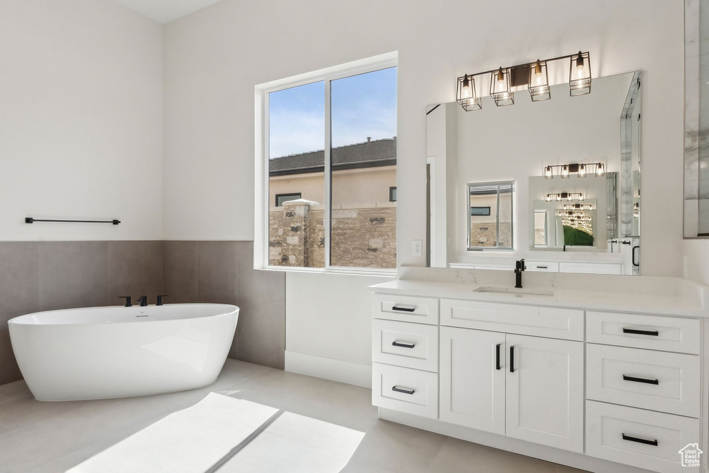 Bathroom with vanity, a shower with door, a freestanding tub, and a wainscoted wall