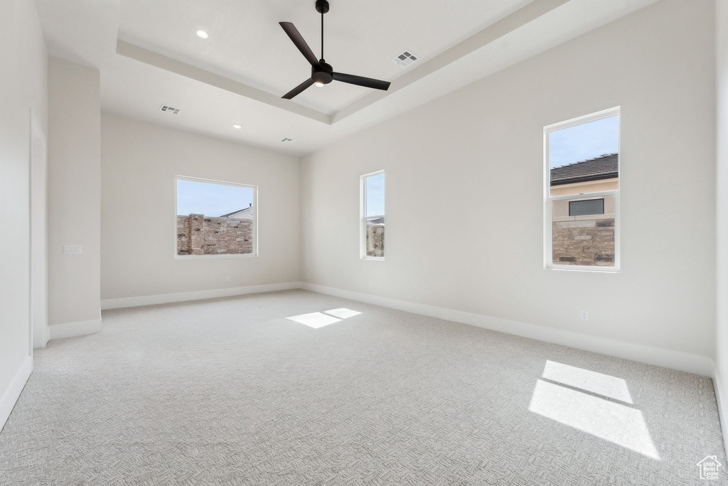 Empty room featuring a raised ceiling, carpet floors, a ceiling fan, recessed lighting, and visible vents