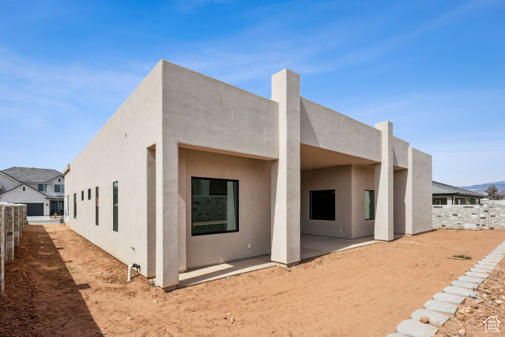Rear view of house with a patio, fence, and stucco siding